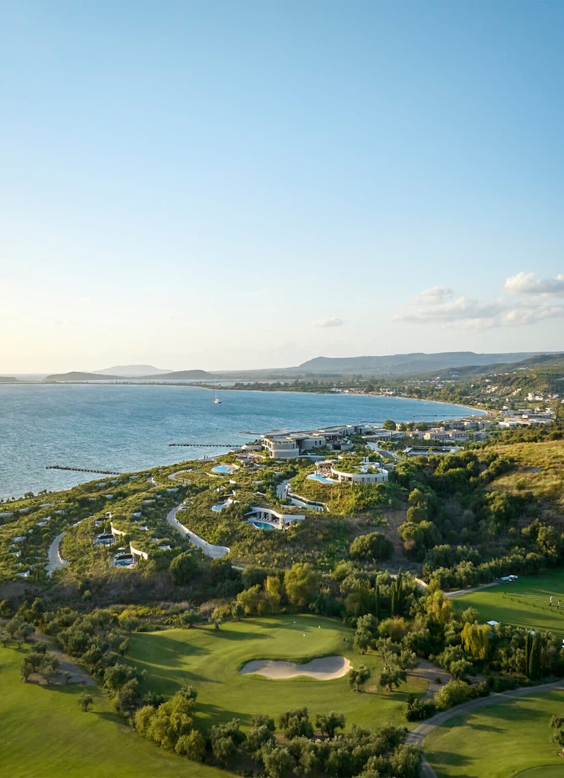 Earth-toned resort landscape rolling toward the sea