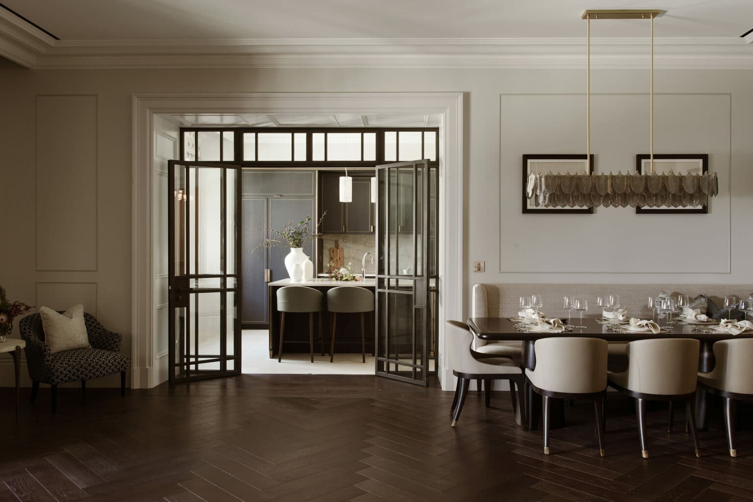 Formal dining room with upholstered chairs around a dark timber table under soft pendant light