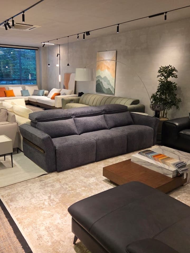 Grey fabric sofa in front of a concrete-look wall with framed art and a floor lamp